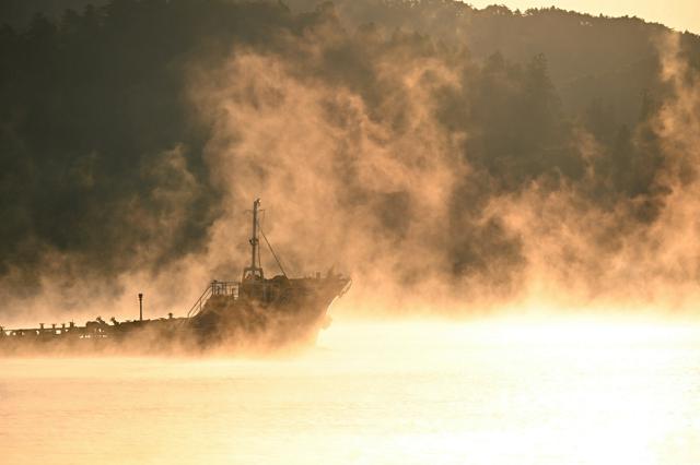 寒さ到来 まるで湯気立つように黄金色に染まる湾 「気嵐」出現